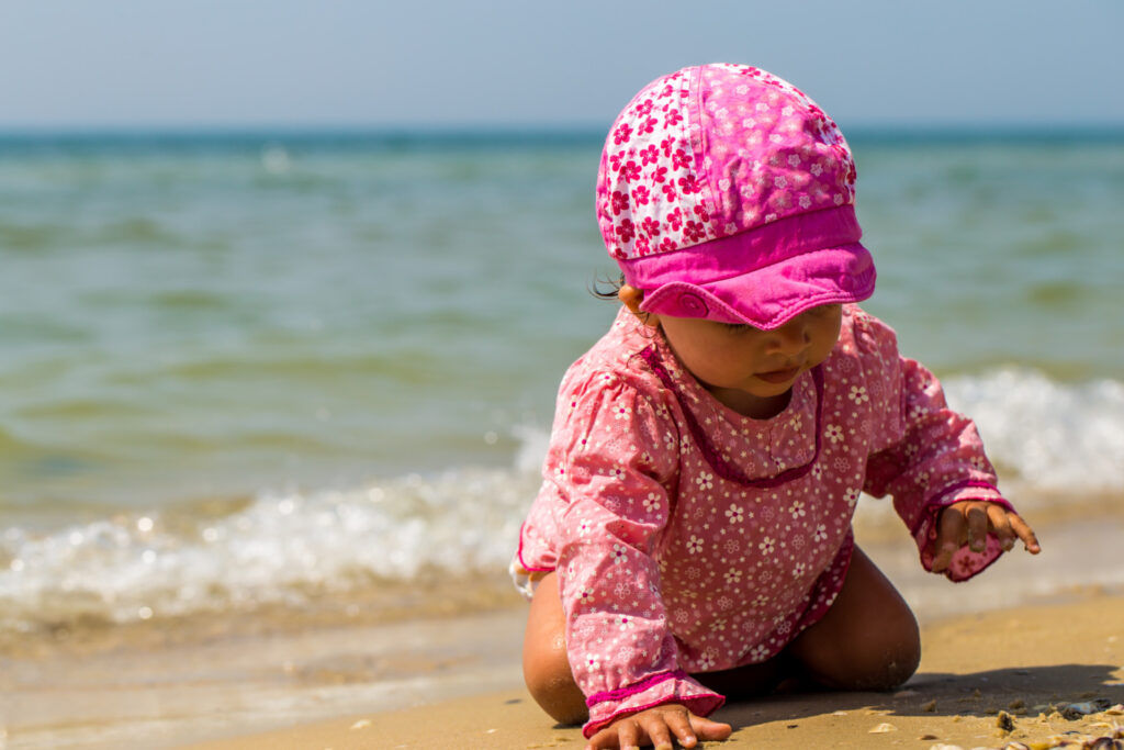 Baby mit Sonnenschutzkleidung
