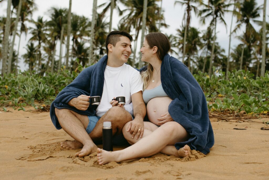 schwanger reisen - paar sitzt am Strand
