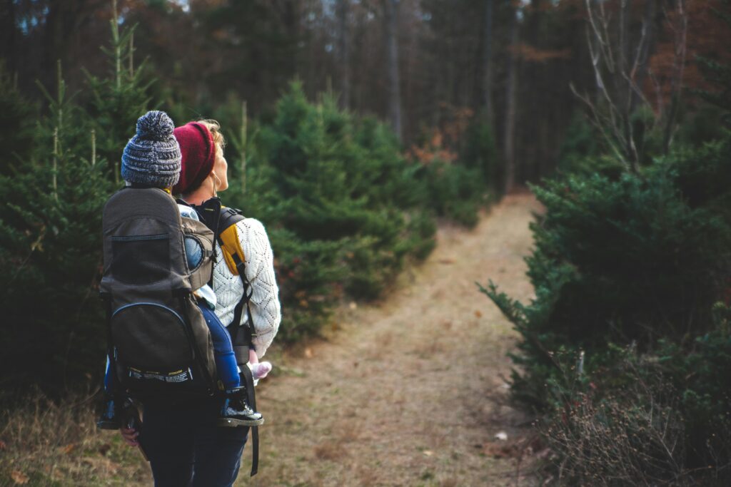 Mutter mit Kraxe beim Wandern mit Kindern