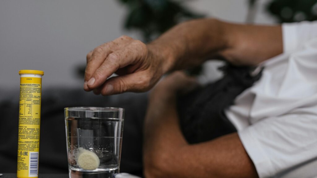 Mann wirft Brausetabletten in Wasserglas